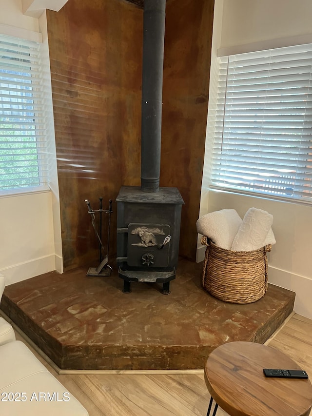 interior details featuring wood finished floors, a wood stove, and baseboards