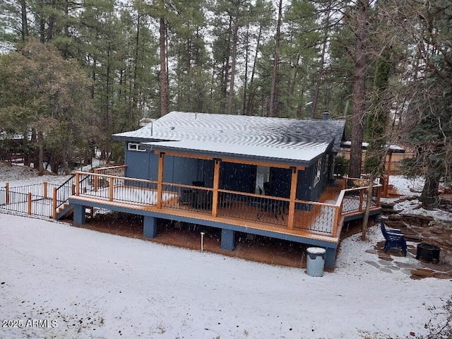 snow covered back of property featuring a deck