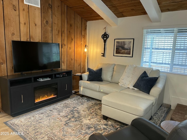 living room featuring light wood finished floors, visible vents, wood ceiling, wood walls, and beam ceiling