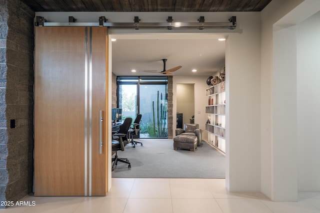 carpeted office with expansive windows, ceiling fan, and a barn door