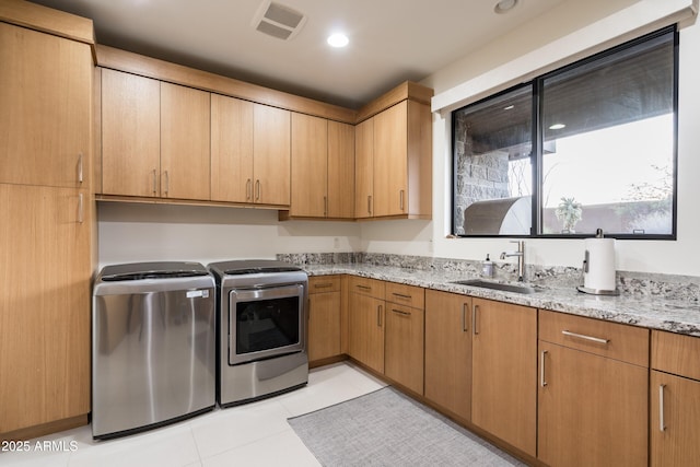 laundry area with cabinets, washing machine and clothes dryer, light tile patterned flooring, and sink