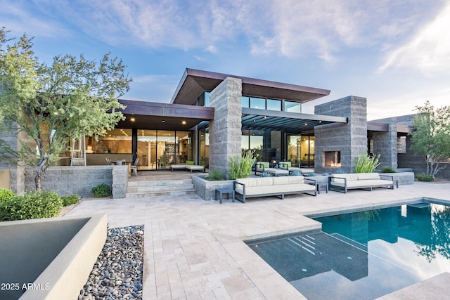 back of house featuring a patio and an outdoor living space with a fireplace