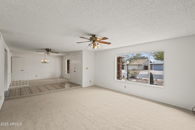 unfurnished living room featuring ceiling fan with notable chandelier, carpet, and a textured ceiling