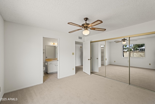 unfurnished bedroom with visible vents, a closet, a textured ceiling, carpet flooring, and connected bathroom