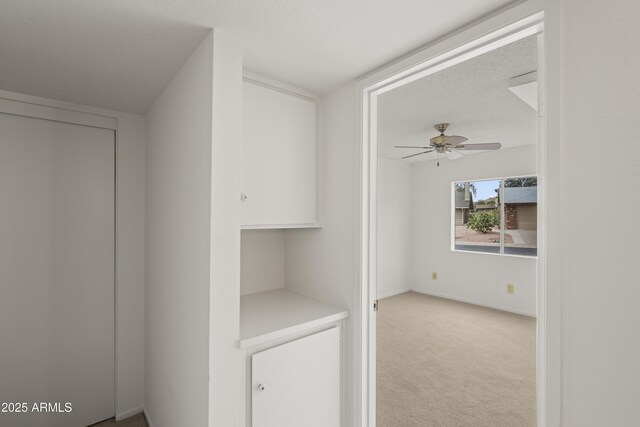 corridor with carpet flooring, baseboards, and a textured ceiling