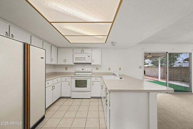 kitchen featuring white appliances, light tile patterned floors, a peninsula, a sink, and light countertops