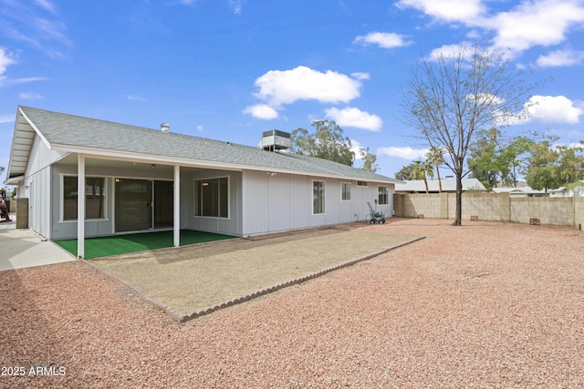 rear view of property with a patio, roof with shingles, and fence