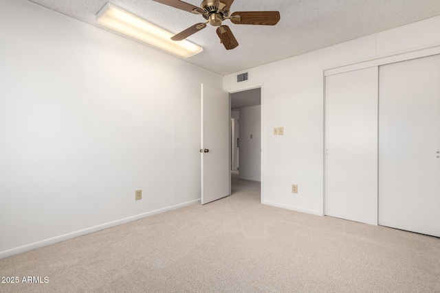 unfurnished bedroom with visible vents, light colored carpet, a closet, and a textured ceiling