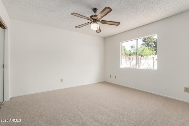 spare room with baseboards, light carpet, a textured ceiling, and a ceiling fan