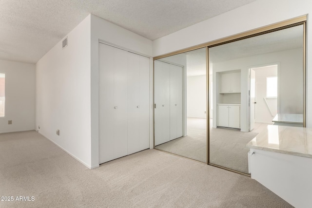 unfurnished bedroom featuring visible vents, a textured ceiling, and carpet floors