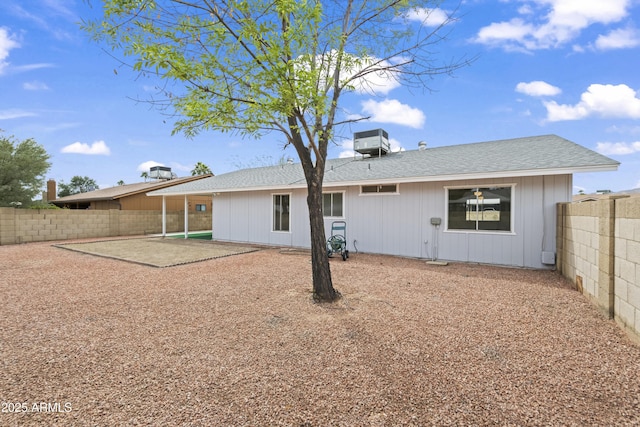 rear view of house with a patio, a fenced backyard, and a shingled roof