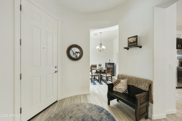 foyer featuring an inviting chandelier, light wood-style floors, and baseboards