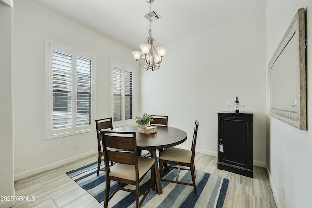 dining space with a chandelier, visible vents, light wood-style floors, and baseboards