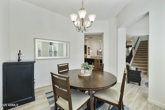 dining area featuring stairway, baseboards, a chandelier, and light wood finished floors