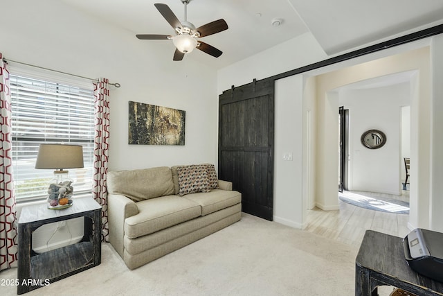 living room featuring ceiling fan, baseboards, carpet, and a barn door