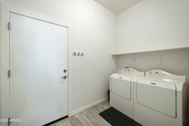 washroom with baseboards, light wood-style flooring, laundry area, and washer and clothes dryer