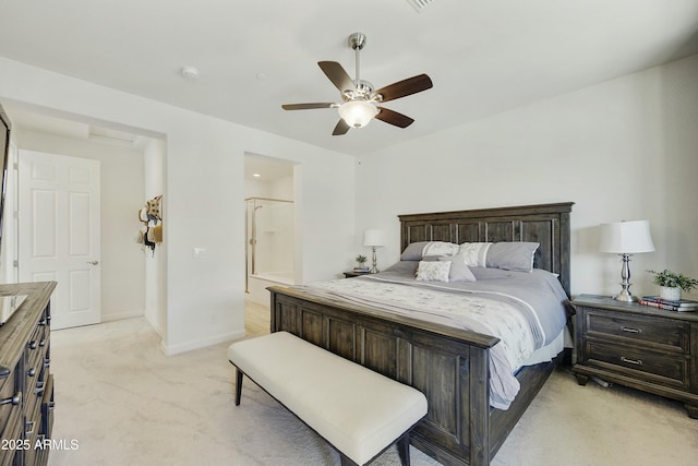 bedroom with connected bathroom, light colored carpet, baseboards, and ceiling fan