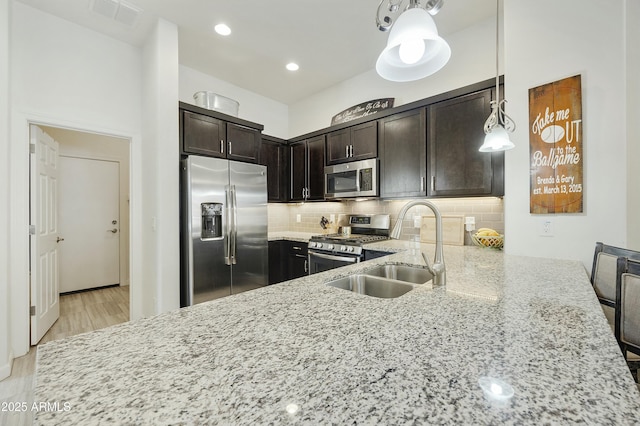 kitchen featuring tasteful backsplash, visible vents, light stone counters, stainless steel appliances, and a sink