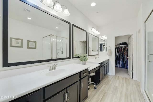 bathroom with visible vents, a walk in closet, a stall shower, recessed lighting, and vanity