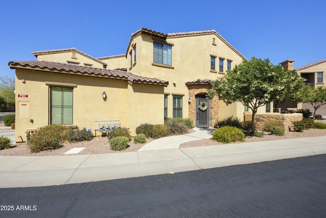 mediterranean / spanish home featuring stucco siding and a tiled roof