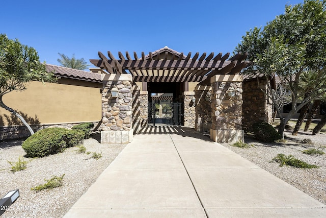 exterior space with a pergola, a gate, stone siding, fence, and a tiled roof