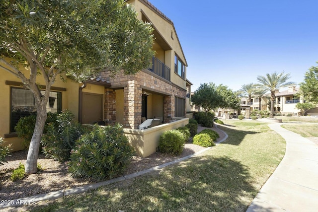 view of home's exterior featuring a yard, stone siding, stucco siding, and a residential view