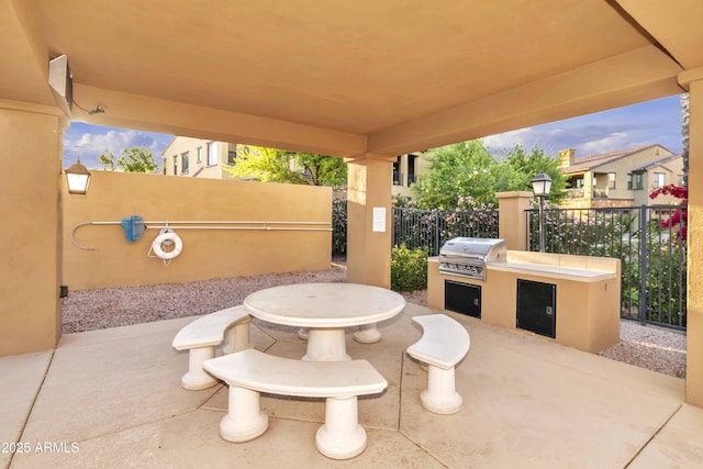 view of patio with an outdoor kitchen, a grill, outdoor dining area, and fence