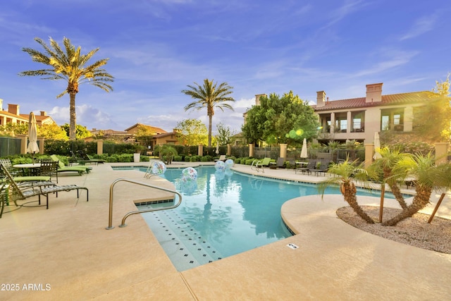 community pool with a patio area and fence