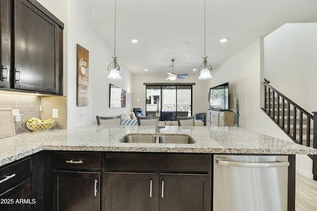 kitchen with light stone counters, dark brown cabinets, stainless steel dishwasher, open floor plan, and backsplash