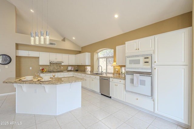 kitchen with light stone counters, a center island, a sink, white appliances, and under cabinet range hood