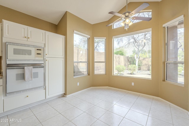 kitchen featuring white appliances, white cabinetry, vaulted ceiling, and light tile patterned floors