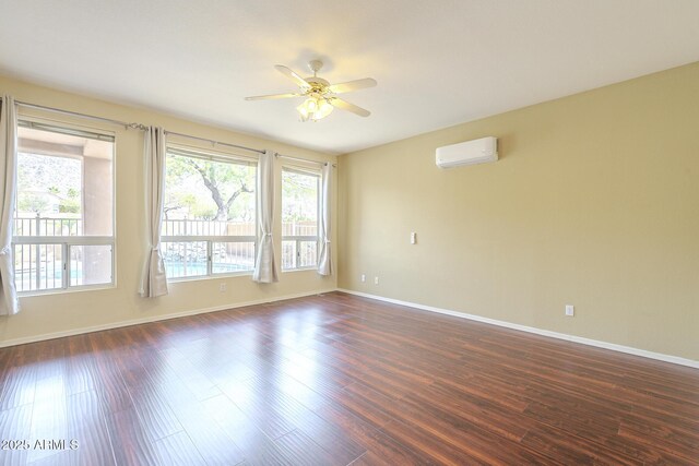 spare room with dark wood-style floors, ceiling fan, a wall unit AC, and baseboards