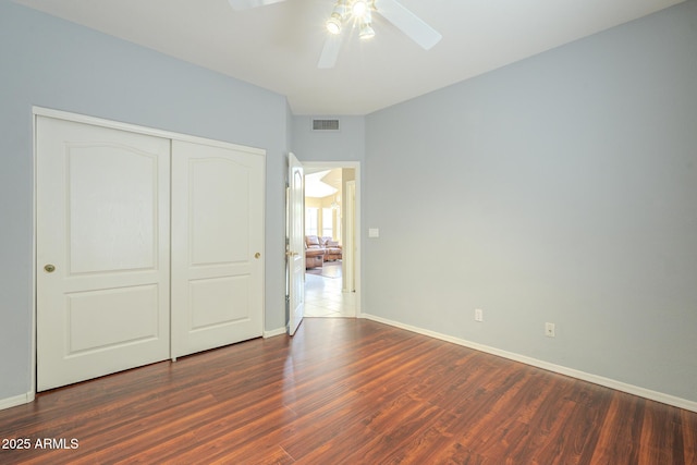 unfurnished bedroom featuring a closet, visible vents, ceiling fan, wood finished floors, and baseboards
