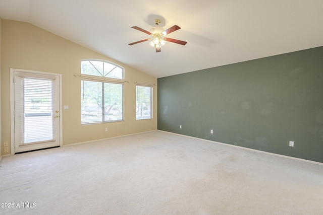 empty room with lofted ceiling, ceiling fan, light carpet, and baseboards