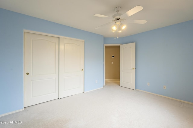unfurnished bedroom with a closet, light colored carpet, and baseboards