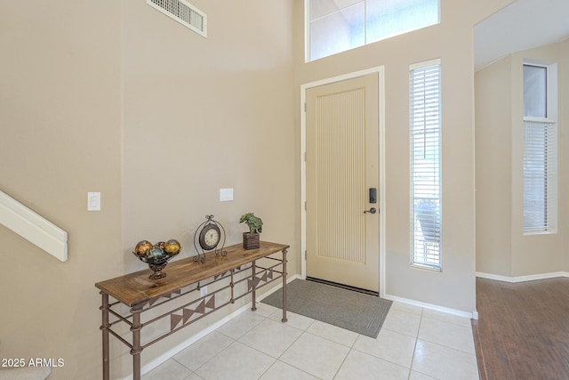 foyer entrance with visible vents, plenty of natural light, baseboards, and light tile patterned floors