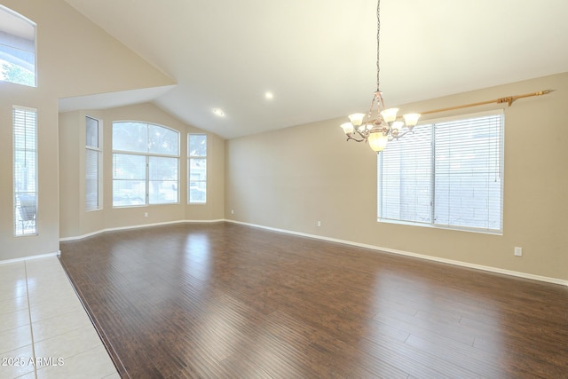spare room featuring lofted ceiling, wood finished floors, and a wealth of natural light