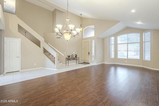 unfurnished living room with baseboards, stairway, light wood-style flooring, and an inviting chandelier