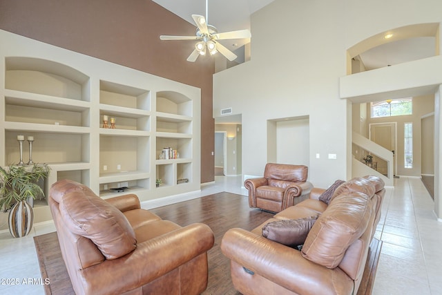 tiled living room featuring ceiling fan, built in shelves, visible vents, and baseboards
