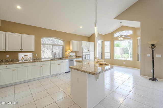 kitchen featuring light tile patterned floors, lofted ceiling, a kitchen island, a sink, and stainless steel dishwasher