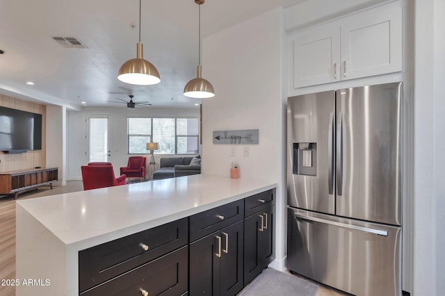 kitchen featuring white cabinetry, decorative light fixtures, stainless steel fridge, and kitchen peninsula