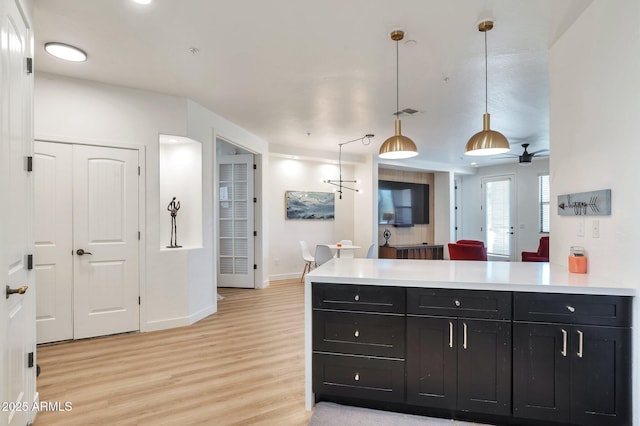 kitchen with pendant lighting, ceiling fan, kitchen peninsula, and light hardwood / wood-style floors