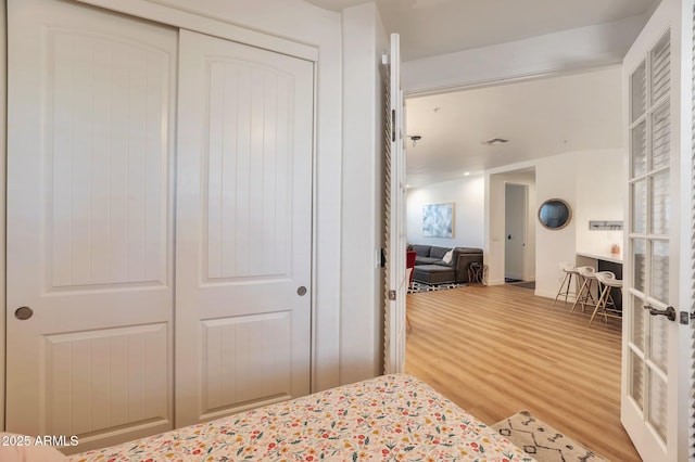 bedroom featuring french doors, wood-type flooring, and a closet