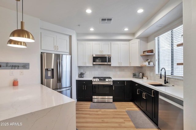 kitchen featuring sink, appliances with stainless steel finishes, hanging light fixtures, tasteful backsplash, and white cabinets