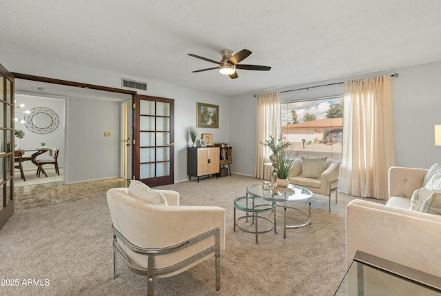 carpeted living area with a ceiling fan, visible vents, a textured ceiling, and baseboards