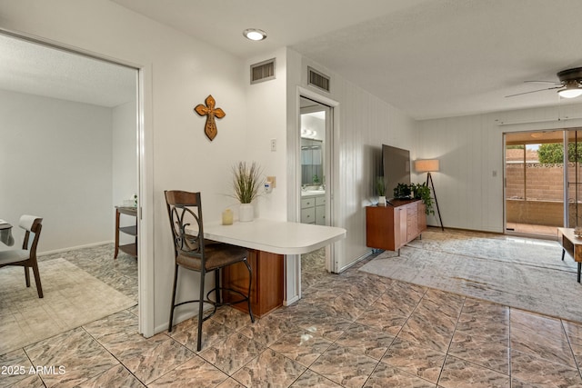 kitchen with baseboards, visible vents, ceiling fan, and a breakfast bar area