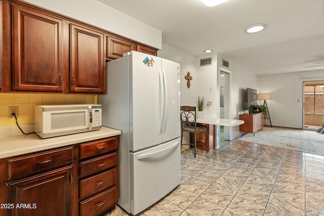 kitchen featuring white appliances, tasteful backsplash, visible vents, and light countertops