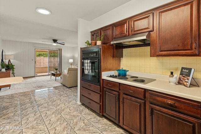 kitchen featuring tasteful backsplash, light countertops, stainless steel electric stovetop, black oven, and under cabinet range hood