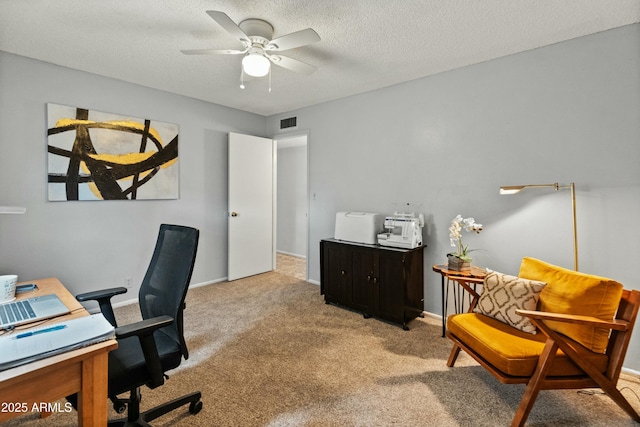 carpeted home office featuring a ceiling fan, baseboards, visible vents, and a textured ceiling