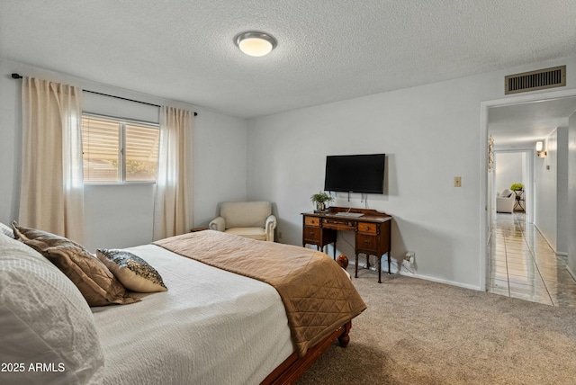 bedroom with a textured ceiling, carpet flooring, visible vents, and baseboards